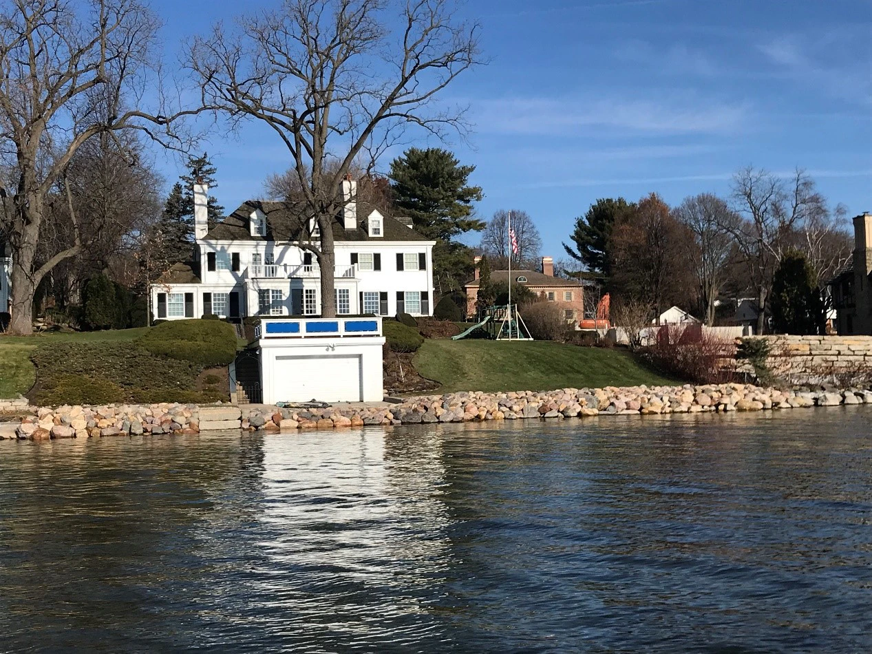 White lakeside house with boathouse and trees